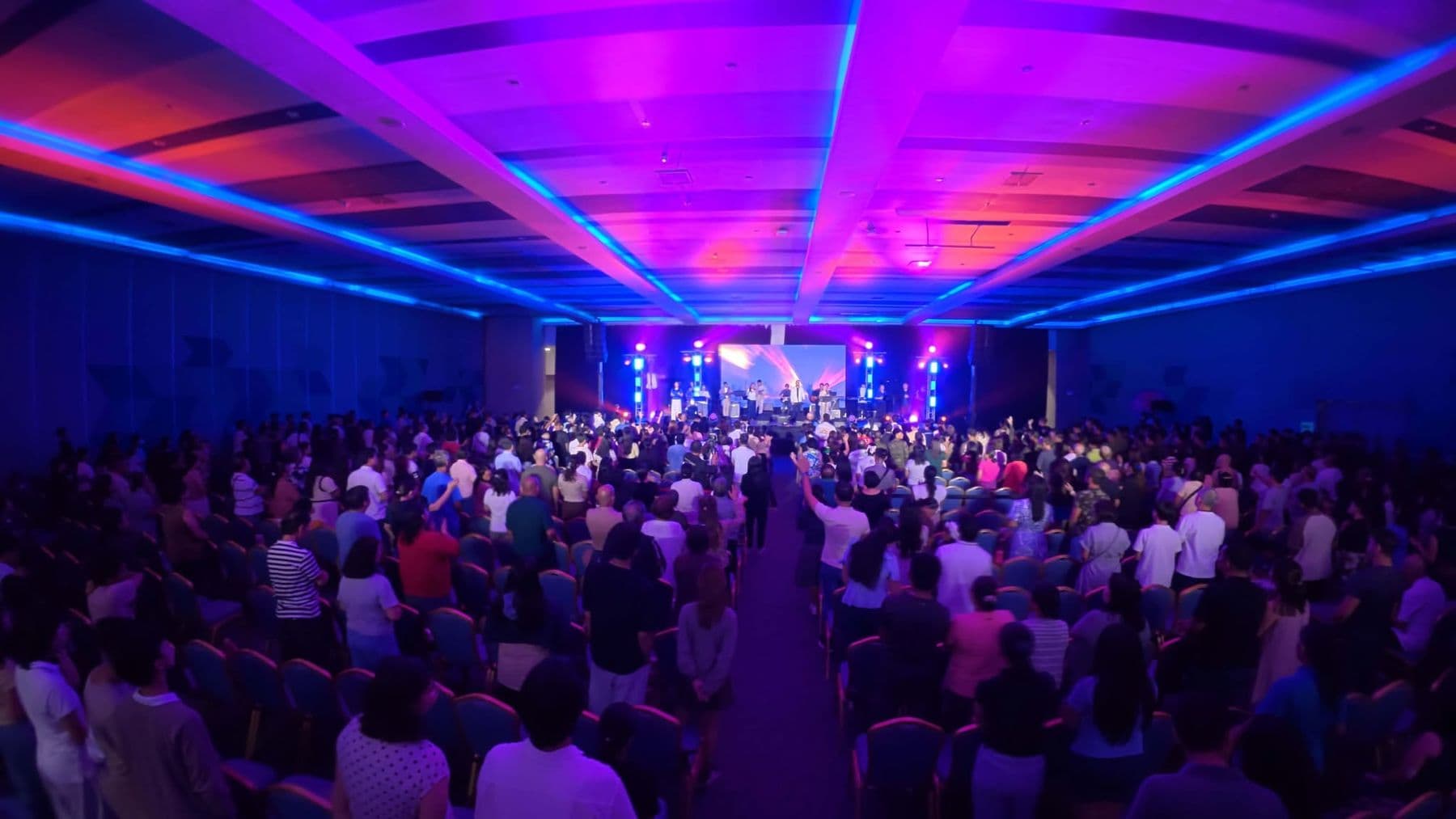 The hall from the back during worship, lit in blue and magenta