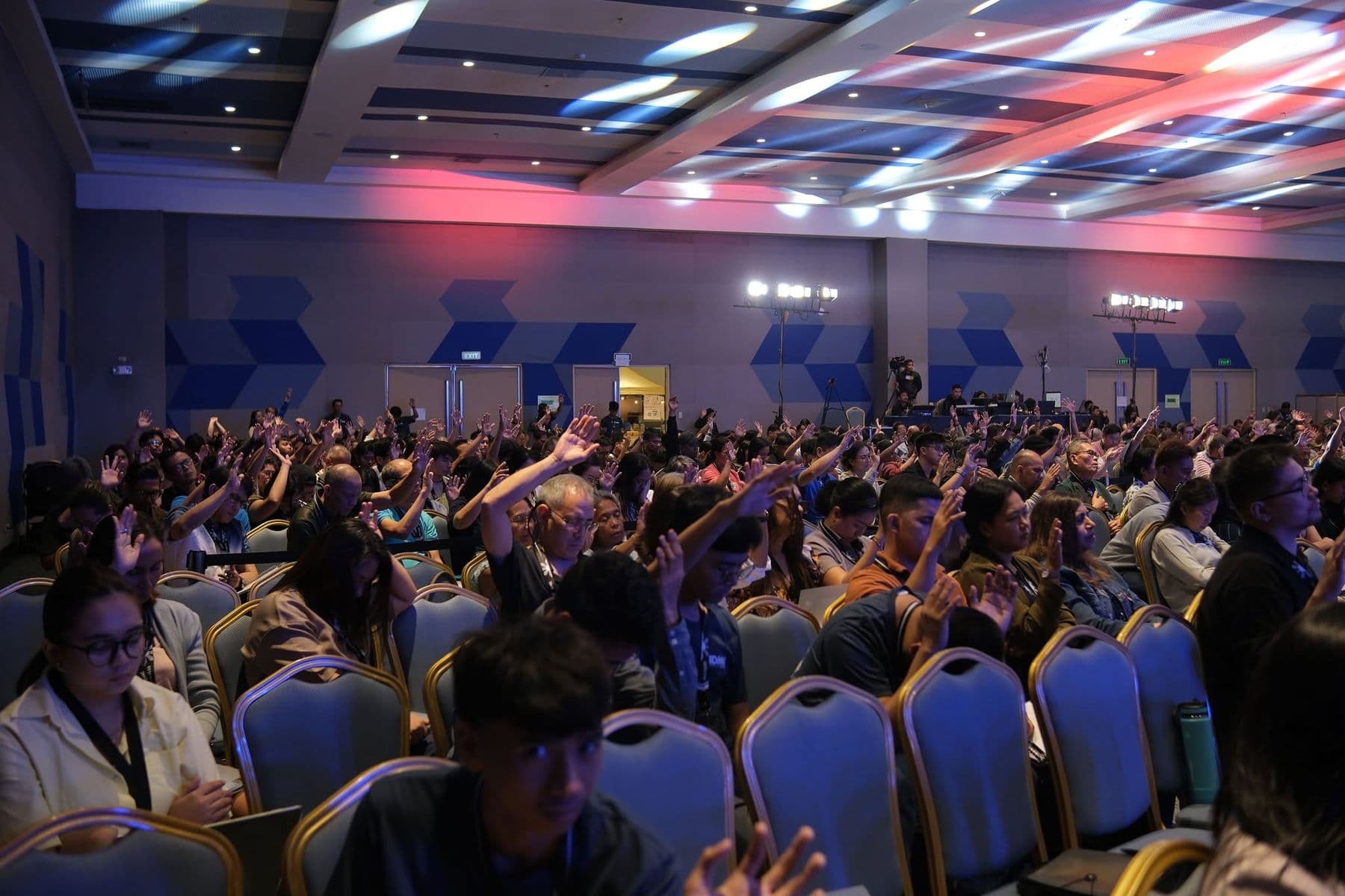 Delegates filling the hall at SMX Bacolod, many with hands raised in worship