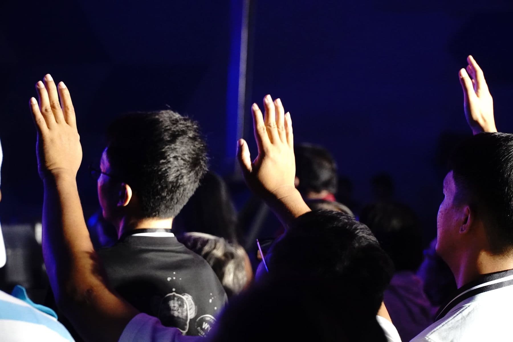 Hands lifted in worship, silhouetted against the stage light