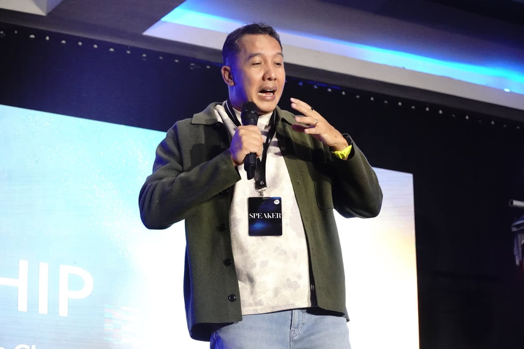 A speaker addressing the hall, microphone in hand