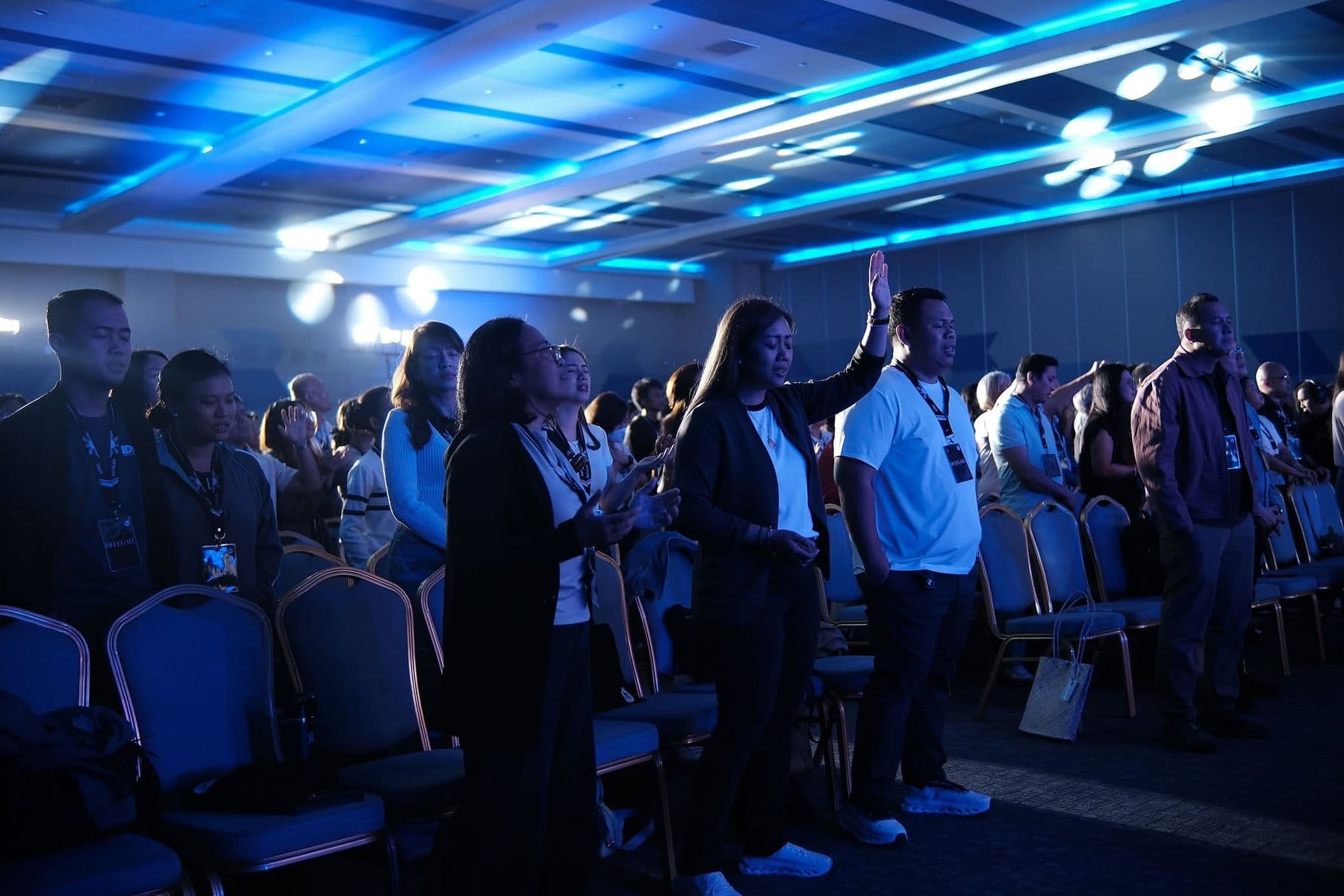 Delegates standing in worship, one with a hand raised